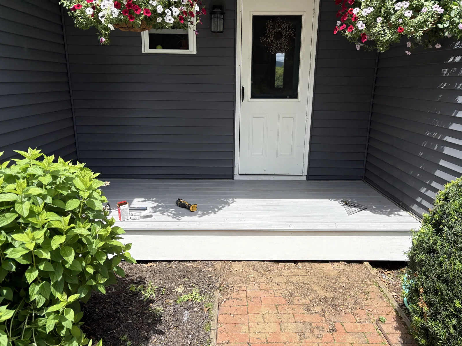 Covered front entry with navy siding and white decking.