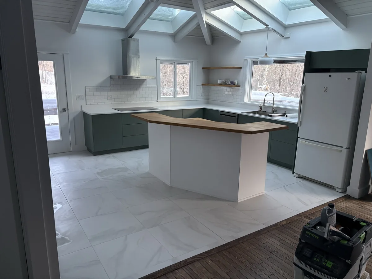 Remodeled kitchen with green cabinets and a large island.