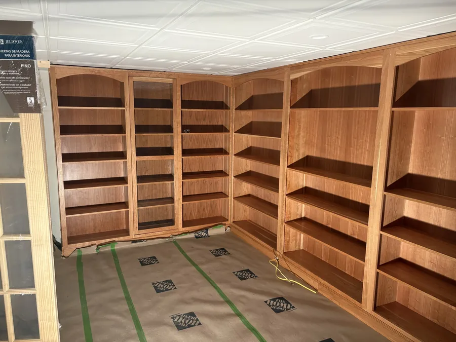 Custom cherry built-in shelving running wall to wall in a home library.