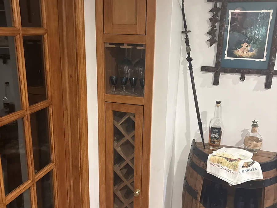 A built-in corner cabinet with glass doors and a diamond wine rack in stained hardwood.