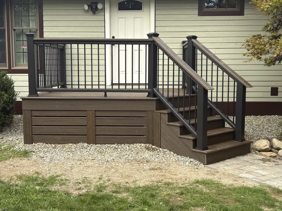 A composite deck with black aluminium railings and matching stairs down to a stone path.