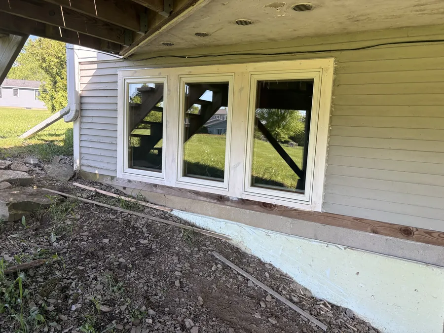 A bank of new basement windows set into fresh framing and a repaired foundation wall.