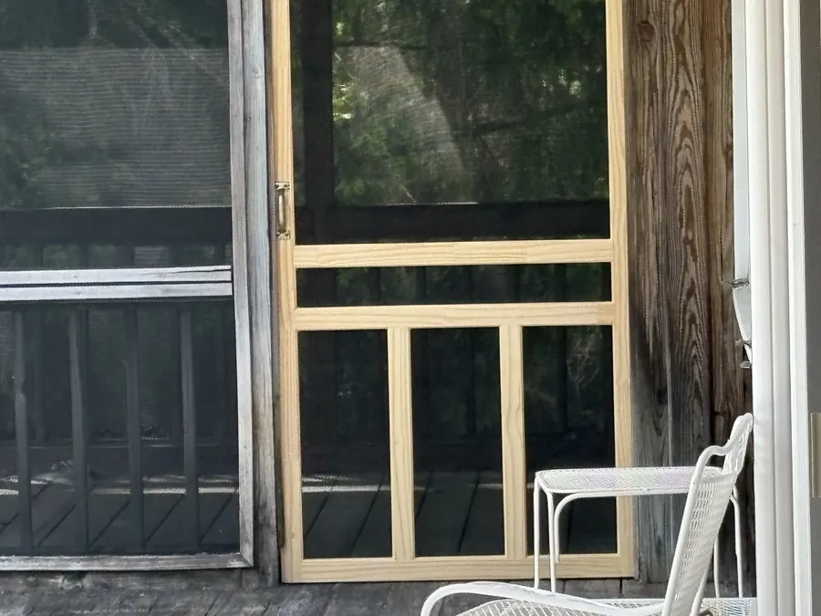 A rebuilt screened porch with a new wood screen door and frame.